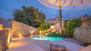 Un área de piscina con paredes de piedra, un banco de madera y una mesa.