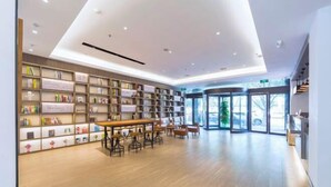 Una biblioteca moderna con estanterías, una mesa de madera y sillas.