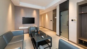 Una habitación de hotel moderna con un televisor de pantalla plana en la pared, una mesa de comedor con sillas y un armario grande.