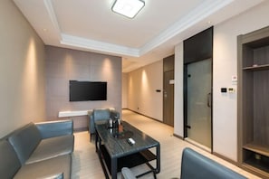 A modern hotel room with a flat-screen TV mounted on the wall, a dining table with chairs, and a large wardrobe. - Wanting Hotel (Zhengzhou Zhenghonghui Yinping Road Subway Station) (Zhengzhou)