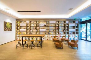A modern library with bookshelves, a long table, and several chairs. - Wanting Hotel (Zhengzhou Zhenghonghui Yinping Road Subway Station) (Zhengzhou)