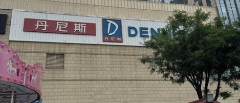 A building with a sign for 'DENNIS' and a smaller sign for '丹尼斯' in a foreign language.