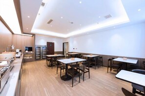 A modern dining area with multiple tables and chairs, a kitchen area, and a refrigerator. - Wanting Hotel (Zhengzhou Zhenghonghui Yinping Road Subway Station) (Zhengzhou)
