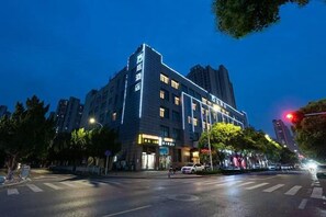 A multi-story hotel with a modern design, located at a city intersection. - Wanting Hotel (Zhengzhou Zhenghonghui Yinping Road Subway Station) (Zhengzhou)