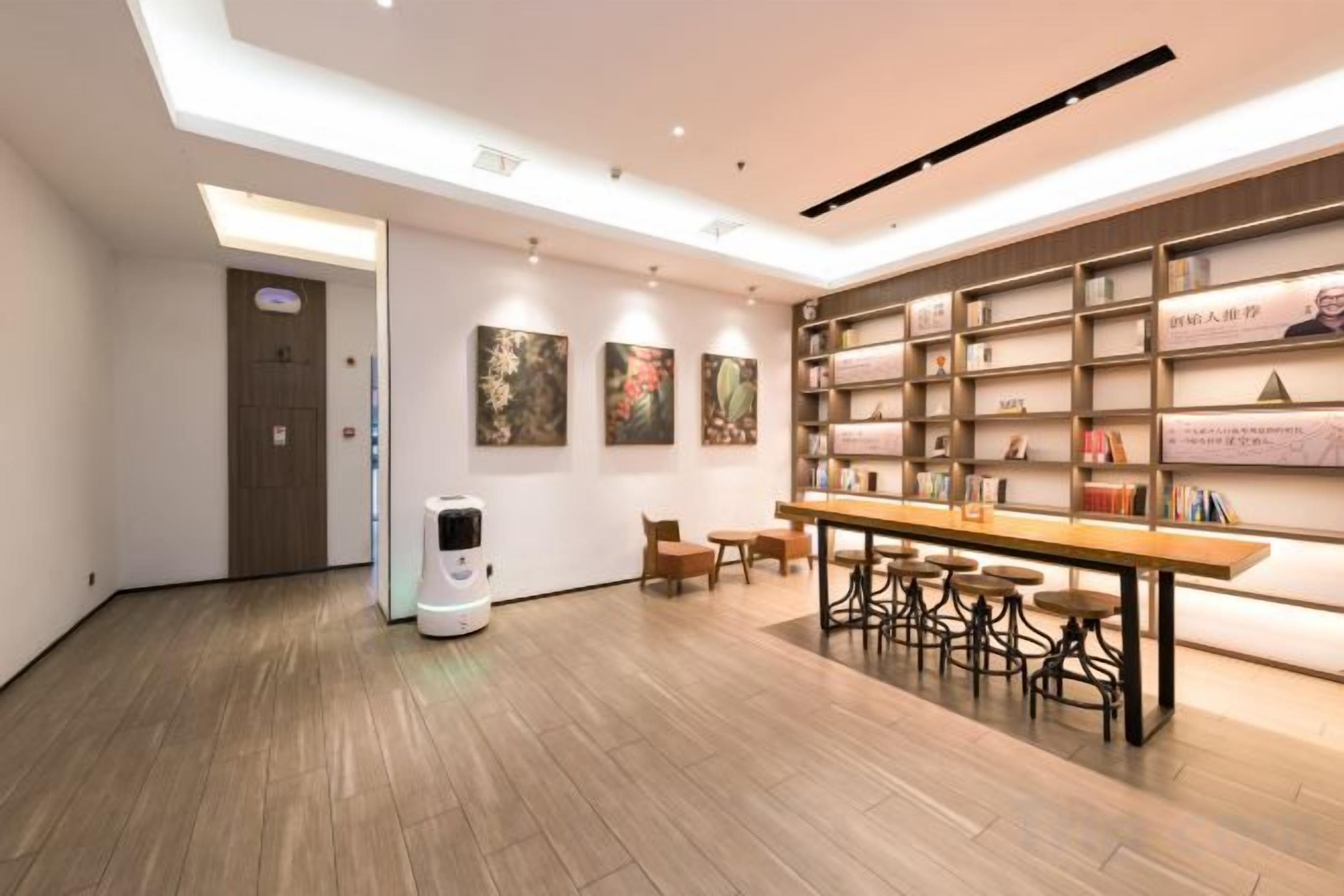 Ein modernes Interieur mit einem Roboter, einem langen Tisch und einem Bücherregal.