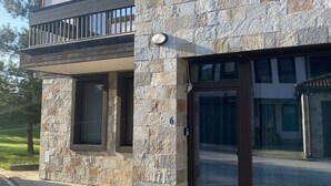 Una casa moderna de dos pisos con fachada de piedra, un balcón y un gran ventanal.