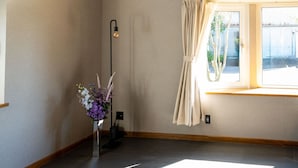 Ein Zimmer mit großem Fenster, einer Stehlampe und einem Blumenstrauß.
