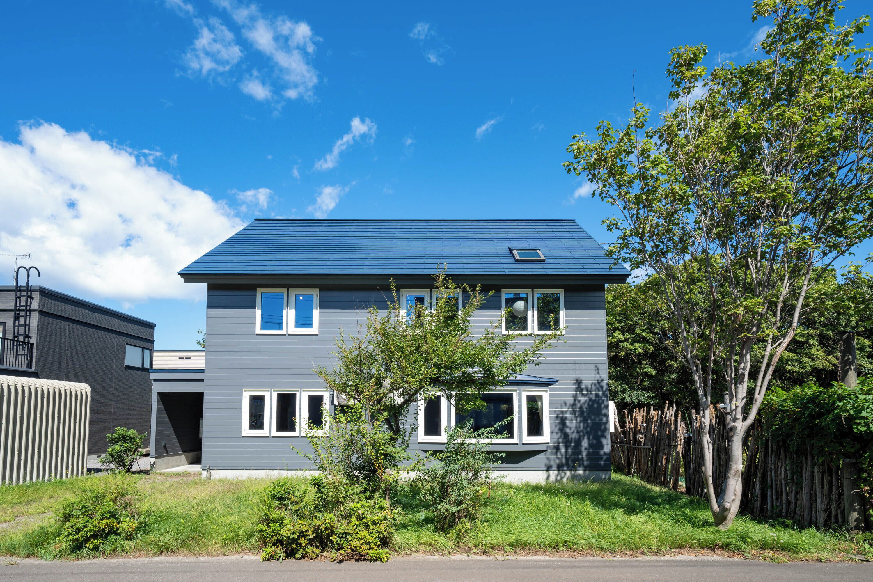 A two-story residential building with a blue roof and white window frames.