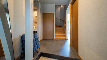 A hallway with a staircase, a seating area with chairs, and a wooden door.