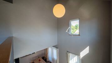 A dining area with a table and chairs, a hanging light fixture, and a window with curtains.