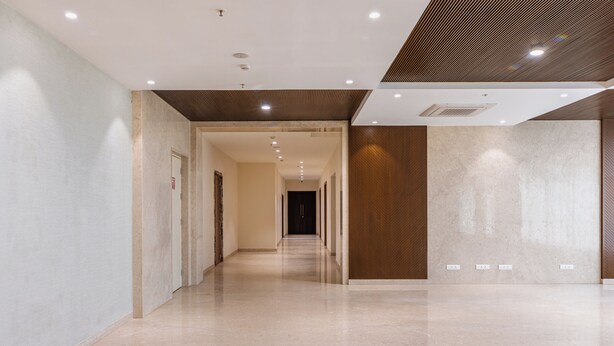 A modern hotel corridor with a polished floor, recessed lighting, and a wooden accent wall. - Hotel Royal Embassy (Erode)