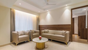 A modern living room with two sofas, a round coffee table, and a ceiling fan. - Hotel Royal Embassy (Erode)