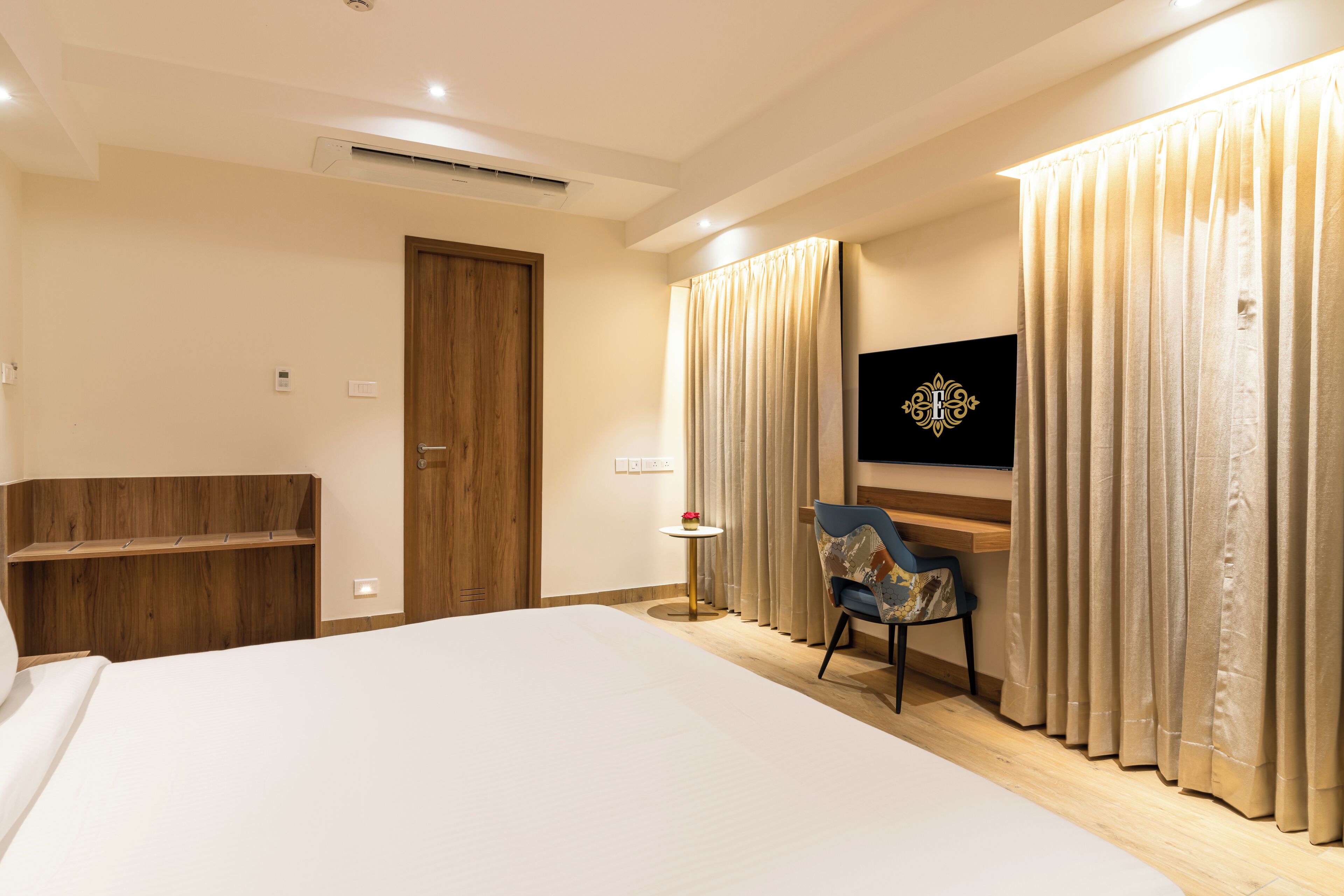 A hotel room with a large bed, a desk with a chair, a television, and curtains.