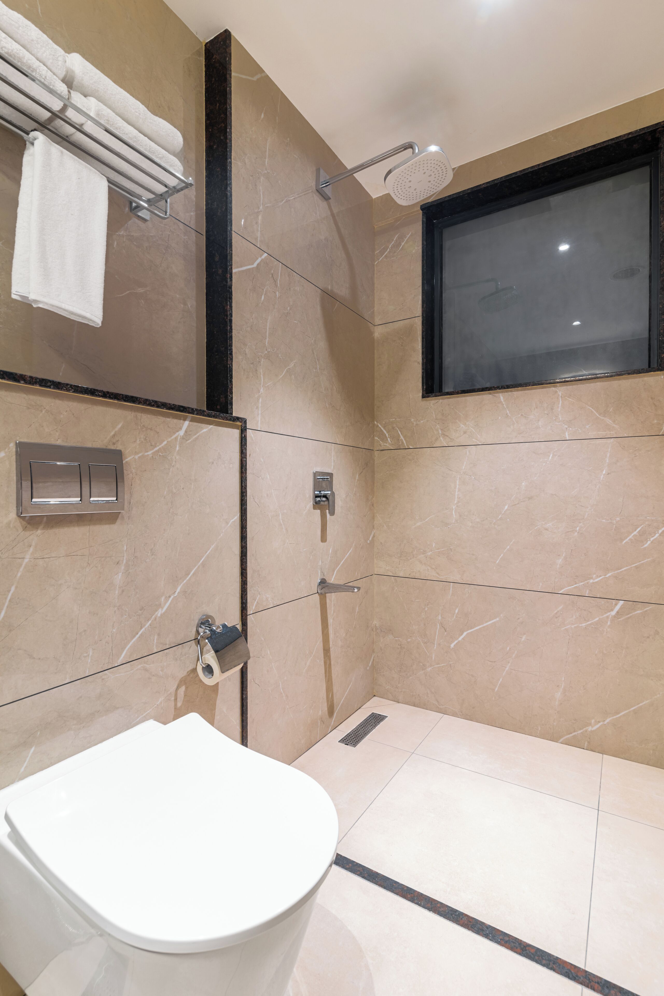 A modern bathroom with a toilet, a shower with a handheld showerhead, and a towel rack.