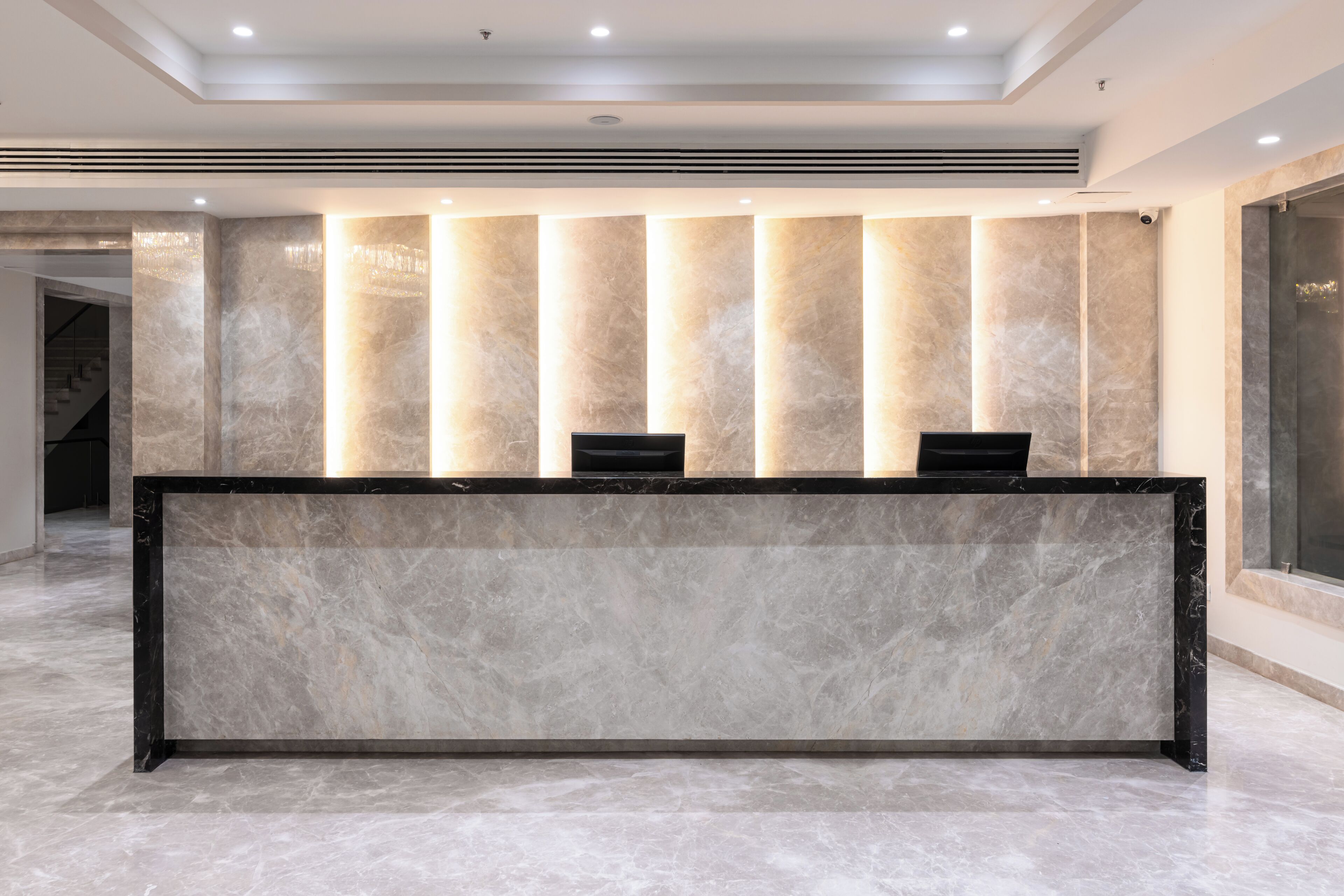 Una reception con un piano in marmo, pannelli retroilluminati, una televisione a schermo piatto e un design moderno e minimalista.