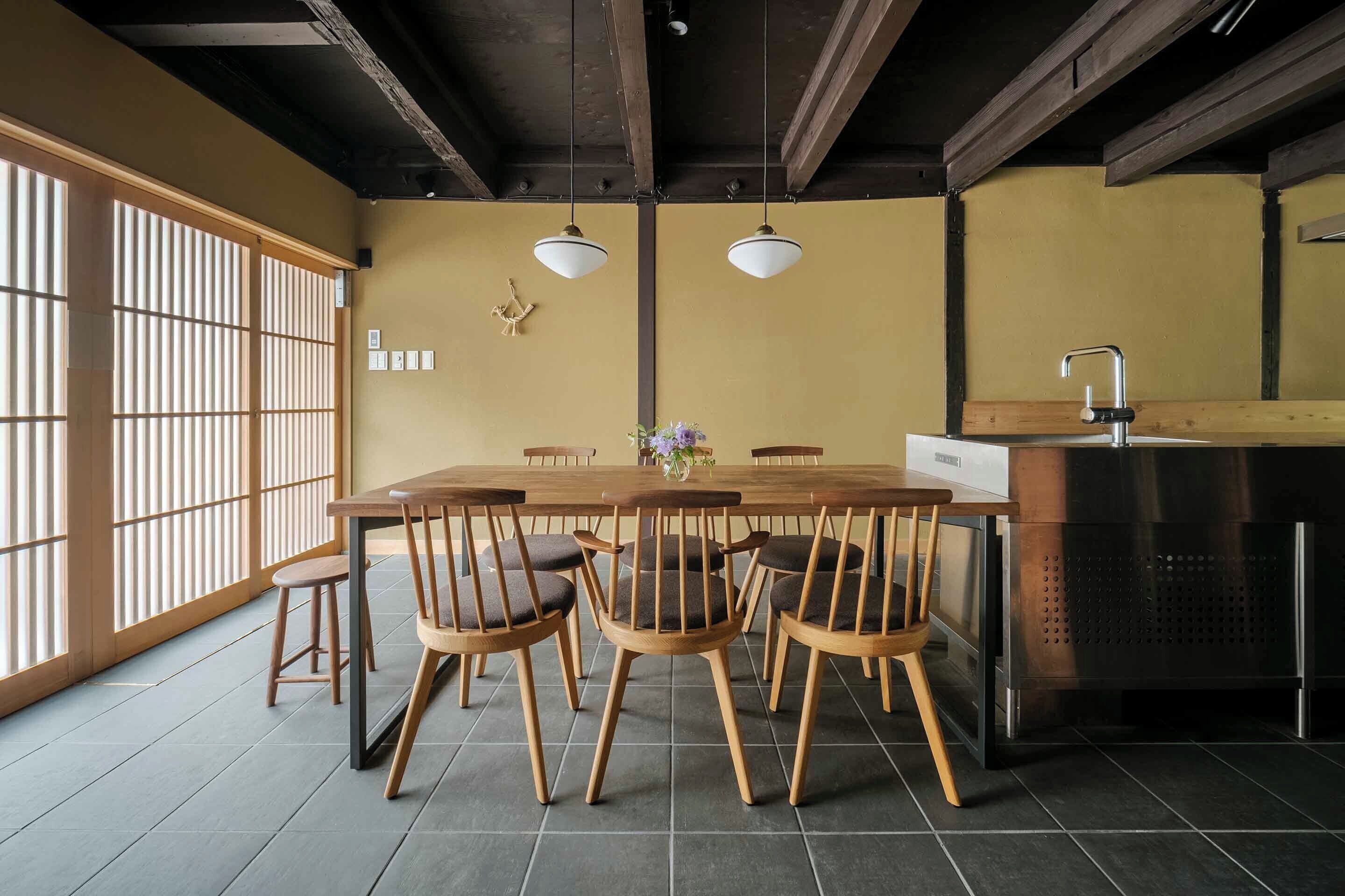 Un coin repas avec une table et des chaises en bois, un coin cuisine avec un évier et une porte coulissante donnant sur une vue agréable.