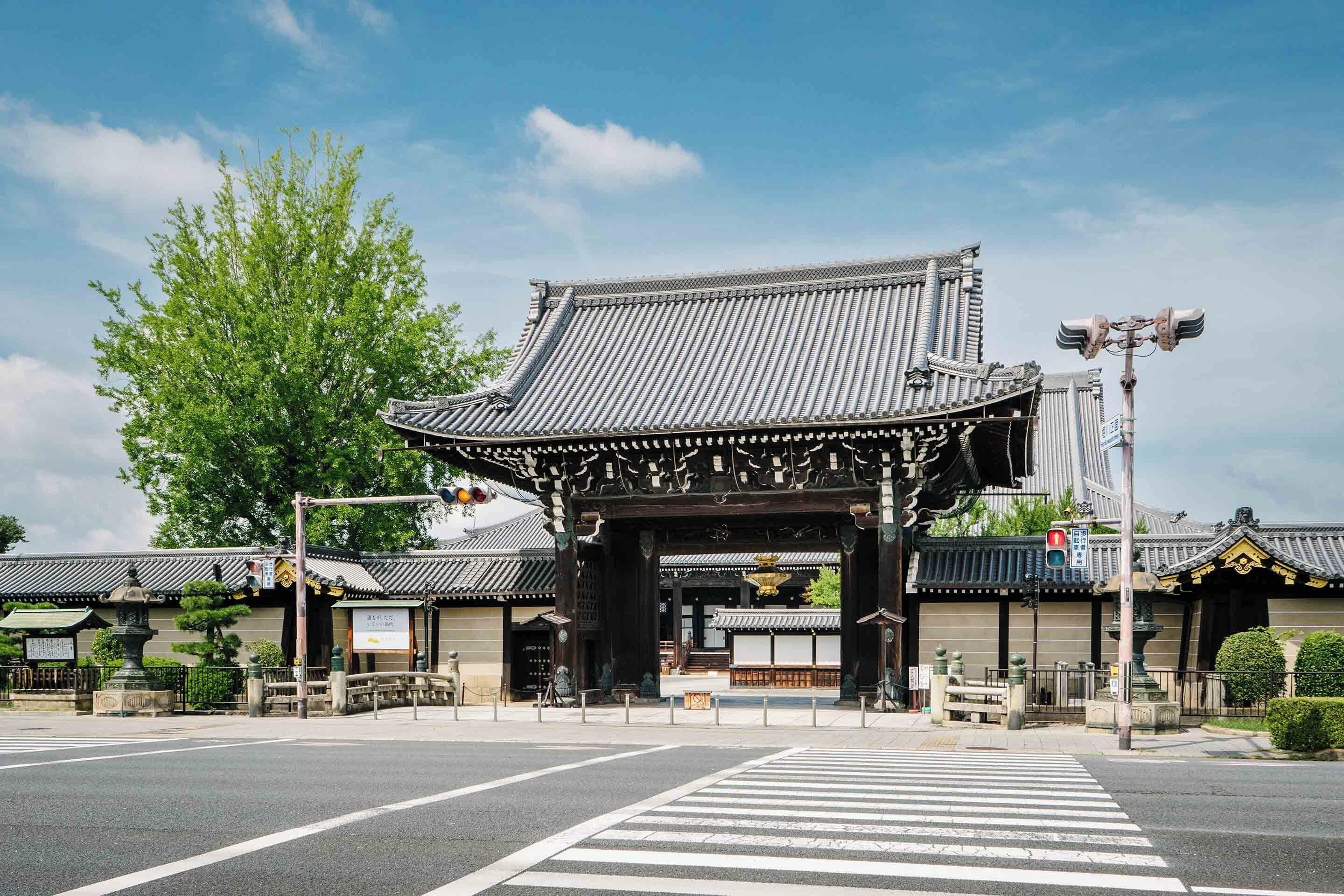 A traditional Japanese gate with a tiled roof and ornate wooden structure.