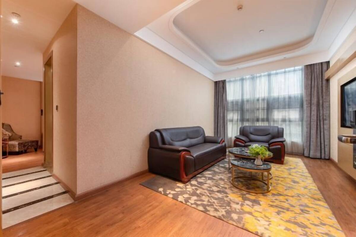A modern living room with a sofa, armchairs, a coffee table, and a large window with curtains.