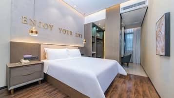 Quarto de hotel moderno com cama, mesa de cabeceira e parede com a inscrição 'ENJOY YOUR LIFE'.