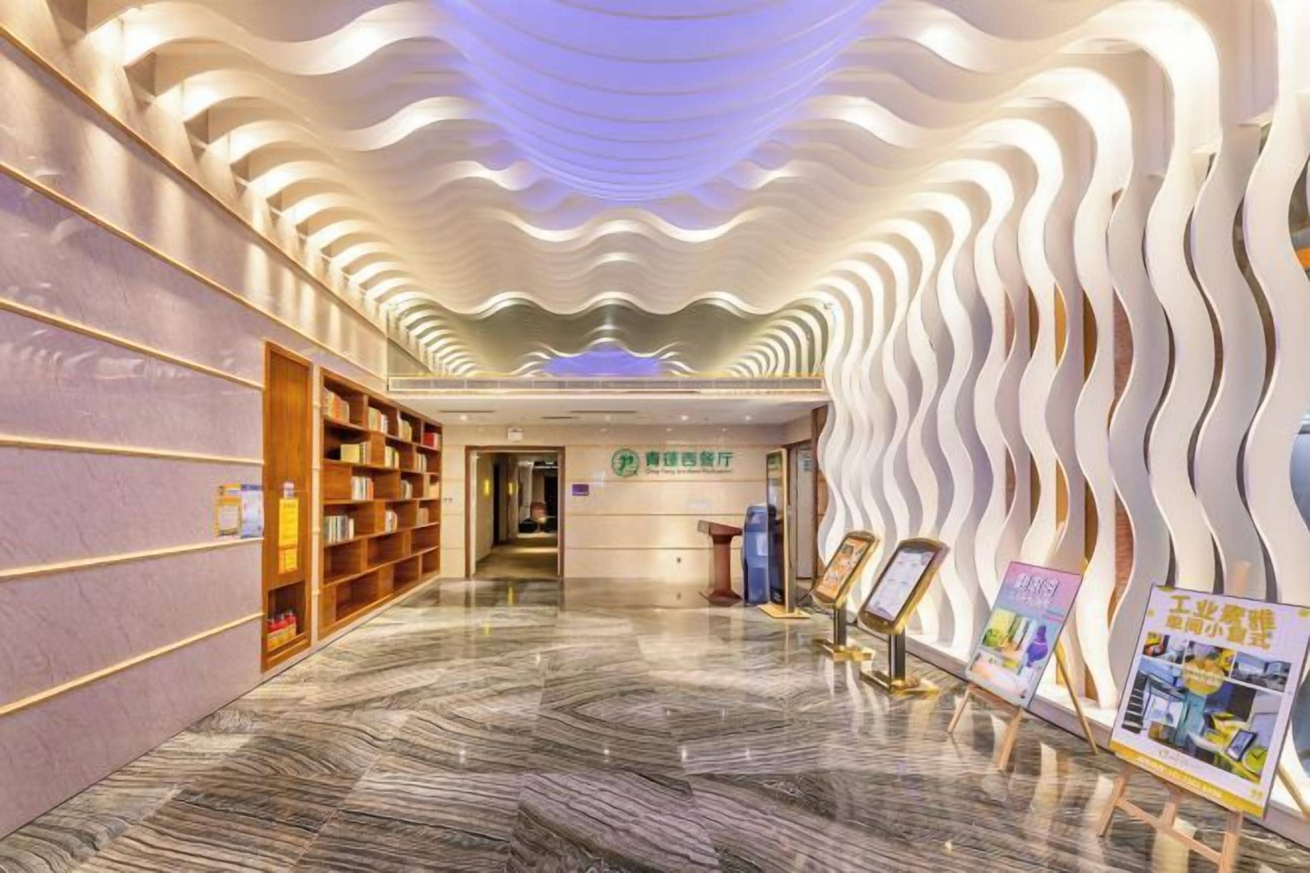 A hotel corridor with a modern design, featuring a marble floor and a wavy ceiling pattern.