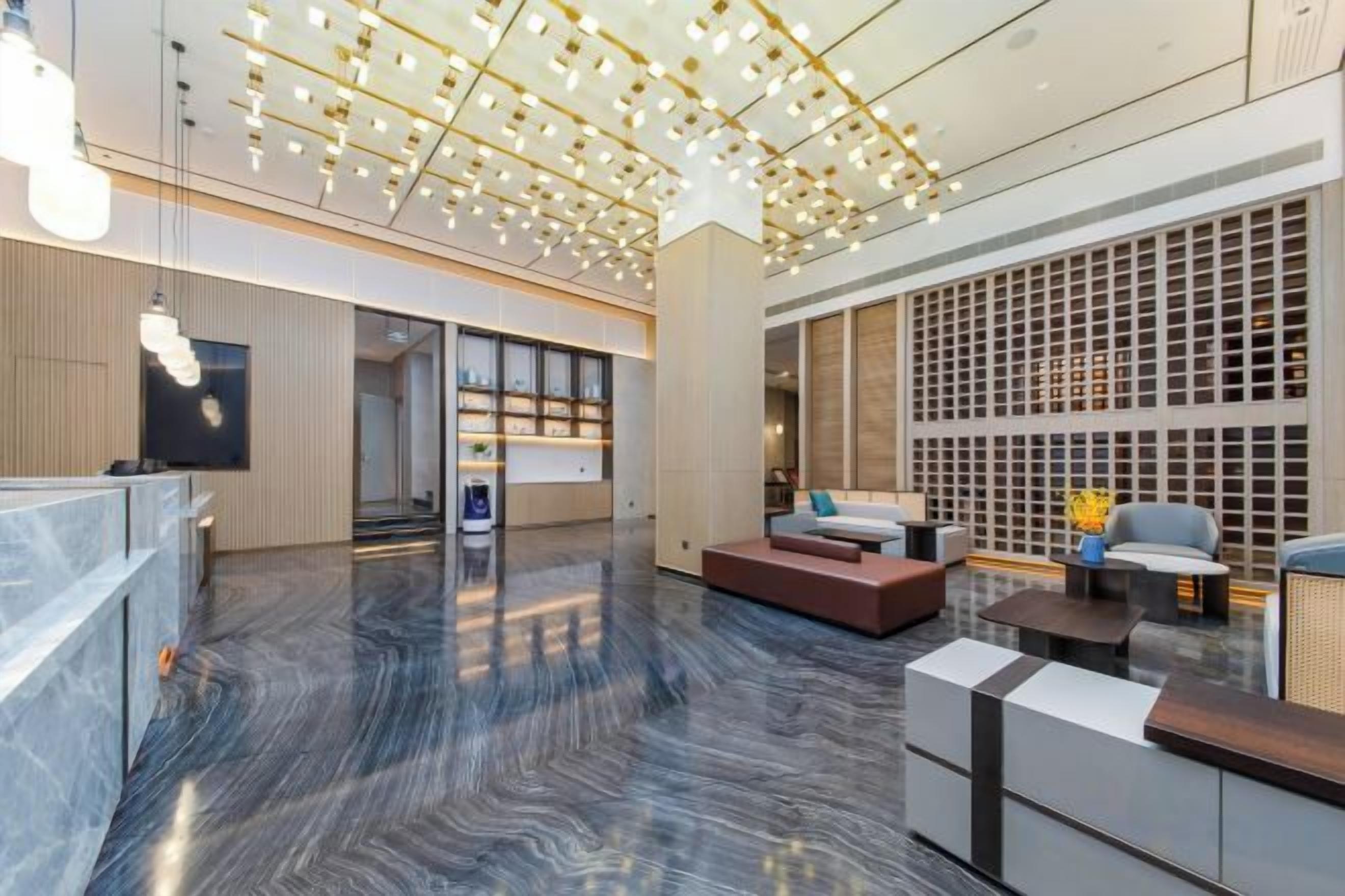 A modern lobby with a reception desk, seating area, and a decorative ceiling.