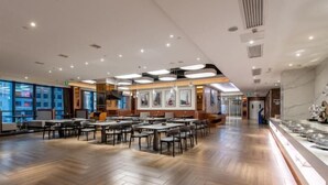 A spacious restaurant with wooden flooring, multiple tables and chairs, and pendant lighting. - Pengke Hotel (Shenzhen North Railway Station Shangmu) (Shenzhen)