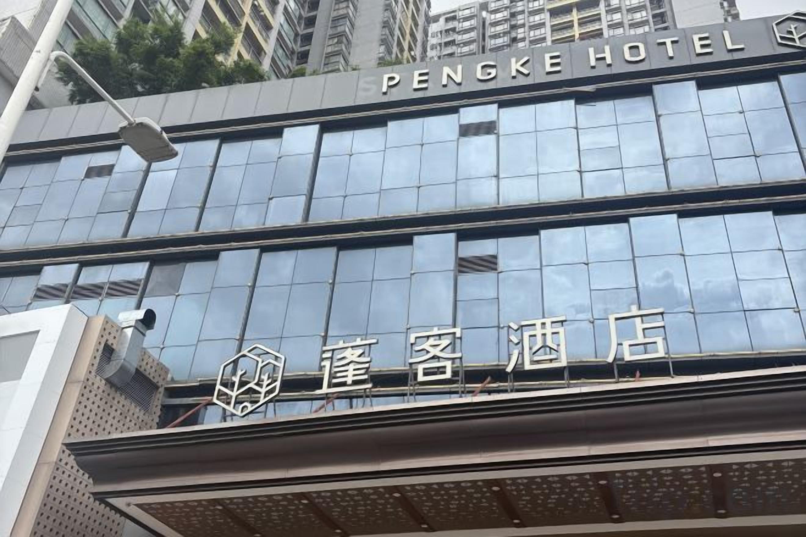 A hotel building with a modern glass facade and signage for 'PENGKE HOTEL' and 'PENGKE HOTEL' in Chinese characters.