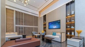 A modern living room with a sofa, coffee table, and TV. There is a decorative wall and a shelf with items. - Pengke Hotel (Shenzhen North Railway Station Shangmu) (Shenzhen)
