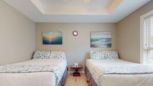 A room with two beds, a small table, and artwork on the walls. - Shared Pool, Pet Friendly, Golf Cart Access (Port Aransas)