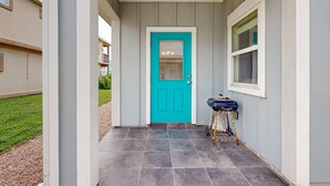 A house entrance with a turquoise door, a small porch, and a grill outside. - Shared Pool, Pet Friendly, Golf Cart Access (Port Aransas)