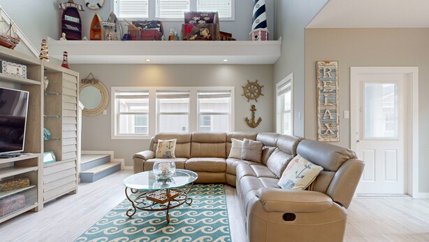 A spacious living room with a large L-shaped sectional sofa, a glass coffee table, and a patterned rug. - Shared Pool, Pet Friendly, Golf Cart Access (Port Aransas)