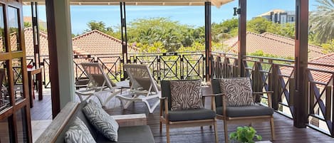 A covered outdoor seating area with a sofa, chairs, and a table.
