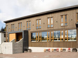 A modern building with a wooden facade, large windows, and a covered outdoor seating area with chairs. - 4 Star Holiday Home in Hisings Backa (Hisings Backa)