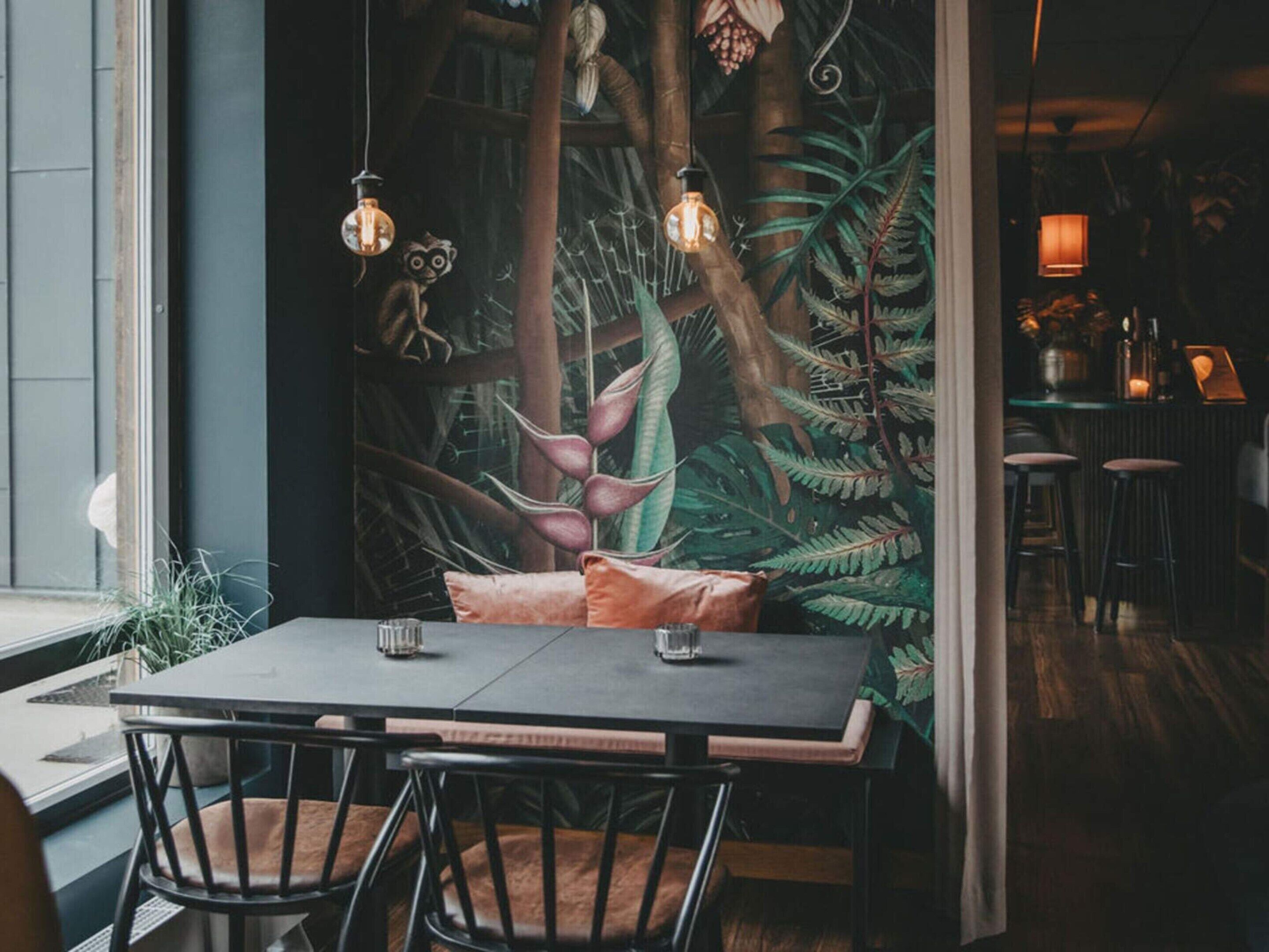 A dining area with a table, chairs, and a mural of a forest scene.