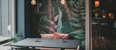 A dining area with a table, chairs, and a mural of a forest scene.
