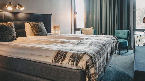 Une chambre d’hôtel avec un grand lit, un bureau, une chaise et une fenêtre avec des rideaux.