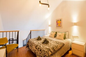 Un dormitorio con cama, mesita de noche, una silla, una escalera y una lámpara fijada a la pared.