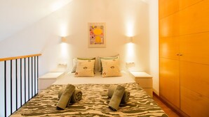A bedroom with a bed, two nightstands, a wooden wardrobe, and a poster on the wall. - Happy Travel Churruca 25 (Málaga)