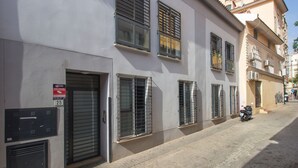 A building with multiple windows, a closed shutter door, and a parked scooter on the sidewalk. - Happy Travel Churruca 25 (Málaga)
