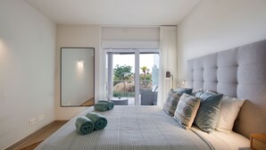 Une chambre dotée d’un grand lit, offrant une vue sur l’extérieur grâce à une porte coulissante, et agrémentée d’une tête de lit moderne.