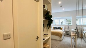 Une chambre à coucher avec un lit, des tables de chevet, un bureau et une fenêtre.