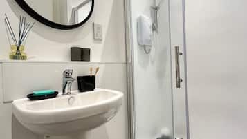 A bathroom with a white sink, a mirror, a glass shower enclosure, and a towel rack.