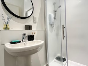 A bathroom with a white sink, a mirror, a glass shower enclosure, and a towel rack.