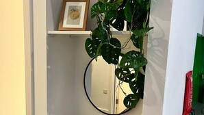 Une salle de bain avec un meuble-lavabo blanc, un miroir rond, un tableau encadré et une plante en pot.