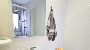 A bathroom with a white sink, a toilet, and a shower. - Seaside Comfort Residence (Larnaca)