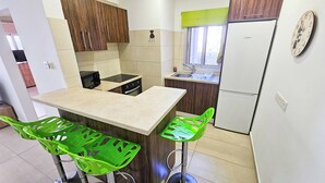 A compact kitchen with a central island, wooden cabinets, and a Bosch refrigerator. - Seaside Comfort Residence (Larnaca)