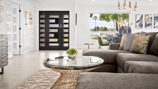 A modern living room with a grey sofa, a glass coffee table, and a view of the outdoors. - Beautiful 4BD/2BA Hilltop Oasis (Phoenix)