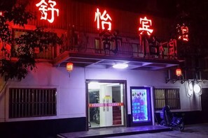 Un bâtiment avec une enseigne au néon, une porte et une moto garée devant.