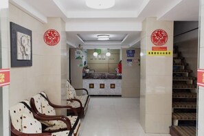 A reception area with a counter, chairs, and a staircase. - Shuyi Hotel (Binhai)