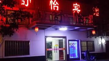 A hotel entrance with a neon sign, a visible entrance door, and a small illuminated display.